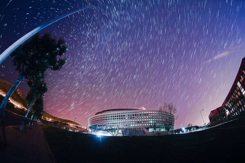 Harbin Institute of Technology Building beneath starry sky captured in long exposure, with meteor-like trails.