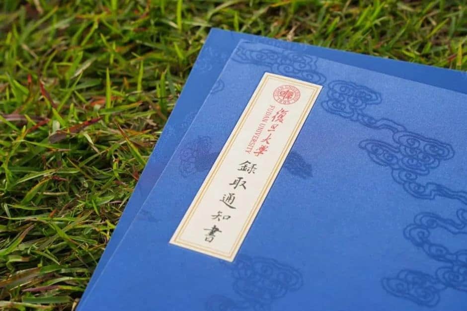 Image shows a blue university acceptance letter from Beijing University, laid on grass, for students applying for study permits and visas to China.