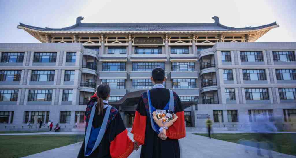 Students in graduation gowns looking at a traditional Chinese building, symbolizing education and cultural heritage in China.