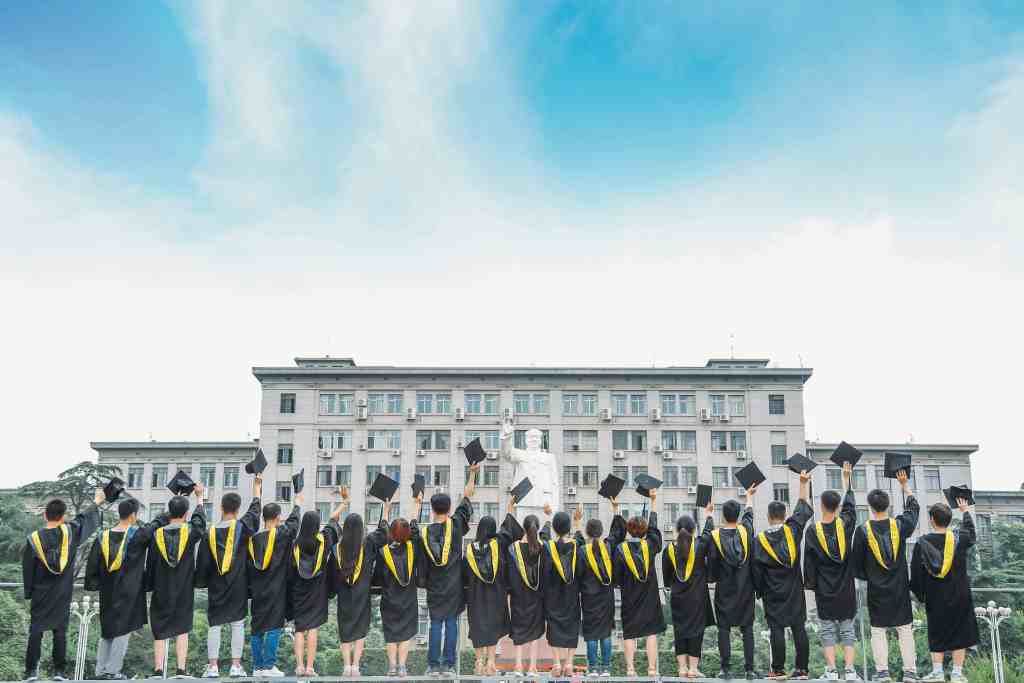 Graduates Celebrating with Caps in the Air in front of Mao Zedong Statue at Huazhong University of Science and Technology