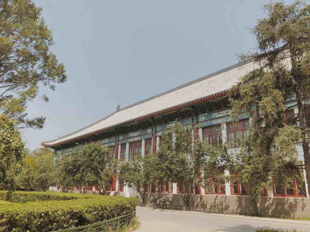 green trees surrounding brown peking university building in Beijing, China
