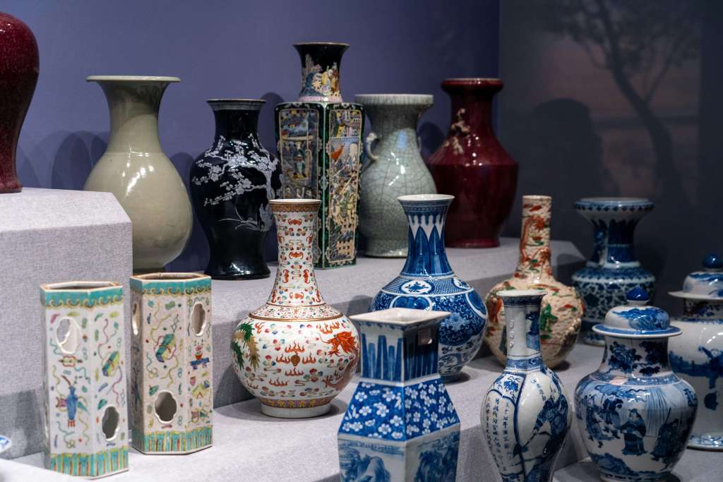 A display of various decorative vases in different shapes and colors, including blue and white porcelain, red-glazed pottery, and intricately patterned ceramics.