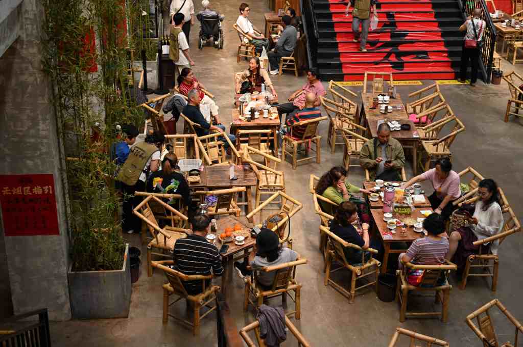 Indoor dining area with wooden tables and chairs filled with people enjoying meals 