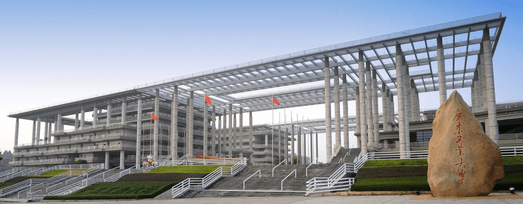 Guangdong University of Technology (GDUT) main building with stone sign and Chinese flags on campus in Guangzhou, China