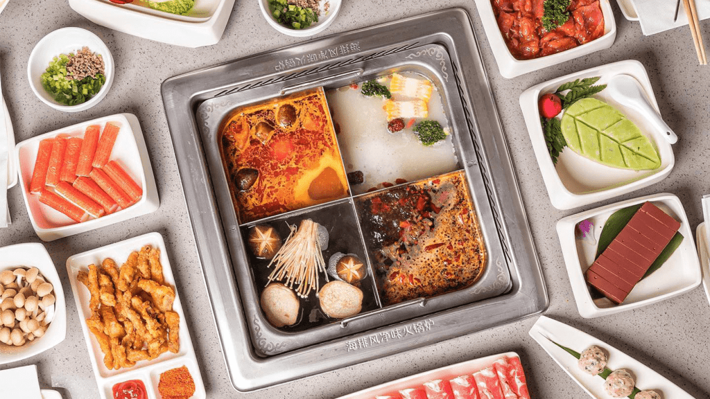 Chinese hot pot with four broth sections surrounded by fresh ingredients — popular food in China