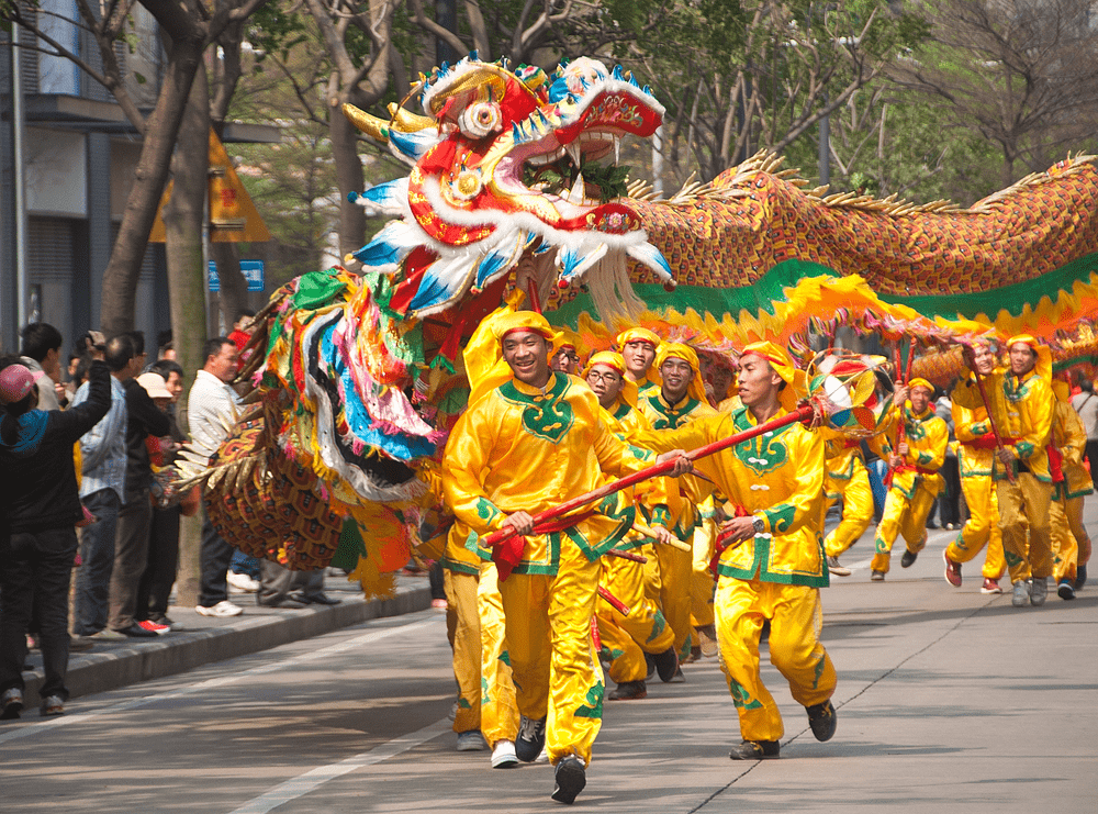 Performers in yellow costumes for a colorful dragon dance street parade to celebrate Chinese customs and traditions 