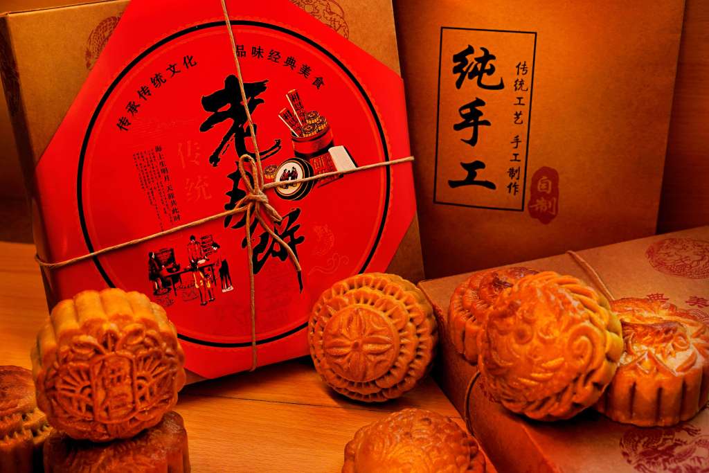 A beautifully arranged display of traditional mooncakes with decorative packaging in vibrant red and brown colors, showcasing festive designs and text.